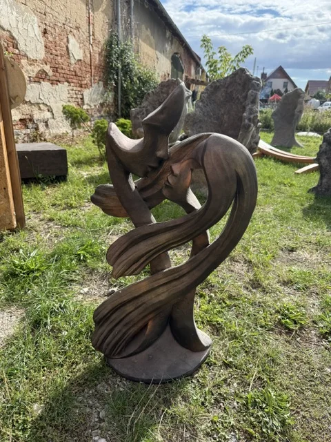 Brązowa figura ogrodowa przedstawiająca stylizowaną parę w objęciach, z płynnymi liniami i wydłużoną, artystyczną formą.