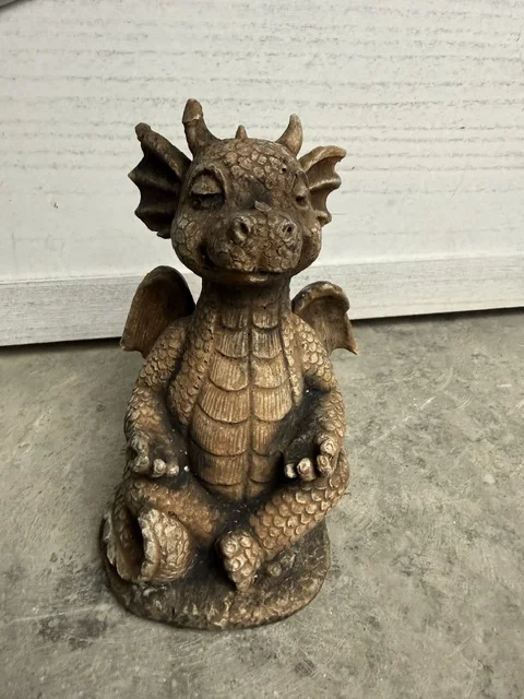 Brązowa figura ogrodowa przedstawiająca smoczka siedzącego w pozycji lotosu, z zamkniętymi oczami, skrzydłami i dekoracyjną fakturą łusek.
