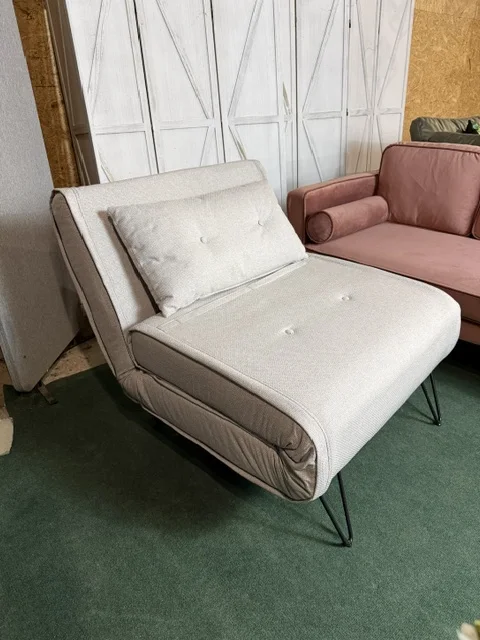 Jasnobeżowa sofa rozkładana jednoosobowa VESTFOLD z poduszką dekoracyjną i czarnymi metalowymi nóżkami, dostępna w Home & Garden Outlet.