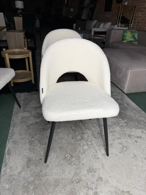 Zestaw 4 białych krzeseł do jadalni ONAGA z tapicerką boucle i czarnymi metalowymi nogami, dostępny w Home & Garden Outlet pod Wrocławiem.
